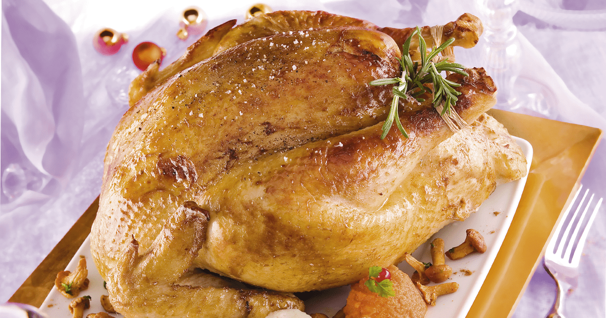 Un chapon cuit avec légumes et herbes dans un plat à four