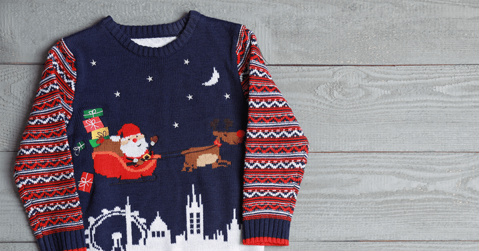 Un pull en maille au design de Noël posé sur le parquet